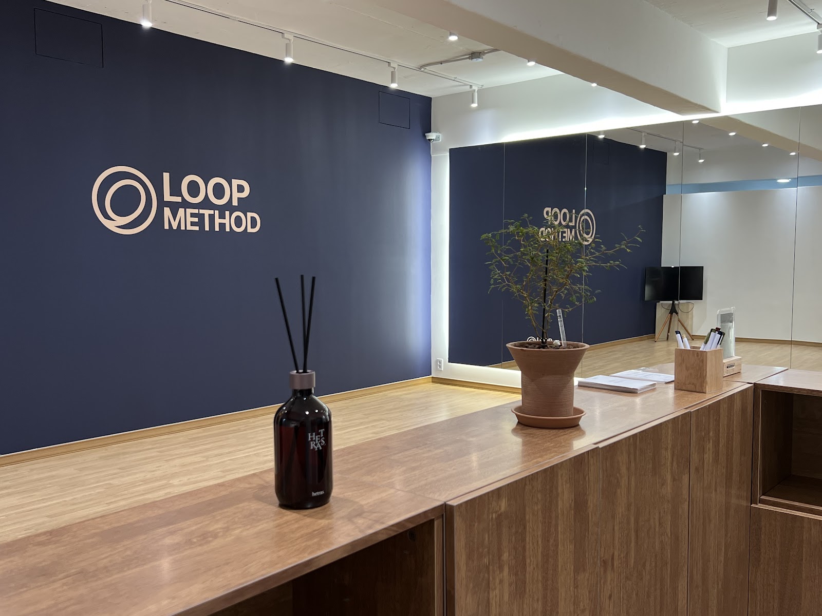 루프메소드 송파본점 리셉션 — 네이비 벽의 LOOP METHOD 로고와 우드 카운터